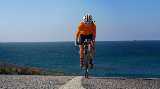 Radfahrer am Meer auf Küstenstraße, sportliches Rennradtraining bei Sonnenschein