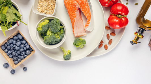 Gesunde Lebensmittel für eine entzündungshemmende Ernährung – frischer Lachs, Brokkoli, Blaubeeren, Tomaten, Nüsse, Haferflocken, Olivenöl und Blattgemüse