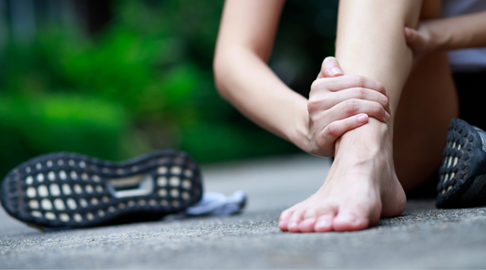 Frau hält schmerzenden Fuß bei Fußarthrose – typische Geste zur Linderung von Gelenkschmerzen durch Arthrose im Sprunggelenk oder Mittelfußbereich