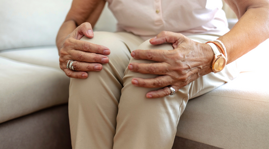 Ältere Frau hält schmerzende Knie bei Arthrose – typische Geste zur Linderung von Knieschmerzen durch Gelenkverschleiß im Alltag