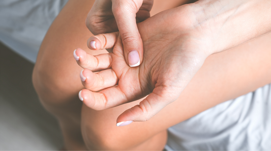 Frau hält schmerzende Hand bei Handarthrose – typisches Anzeichen für Arthrose im Handgelenk mit Schmerzen, Steifheit und eingeschränkter Beweglichkeit