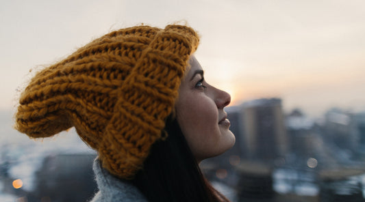 Frau mit Mütze blickt nachdenklich in den Winterhimmel