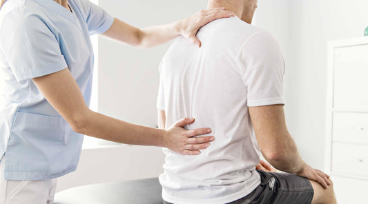 Physiotherapeut behandelt Rückenschmerzen eines Patienten
