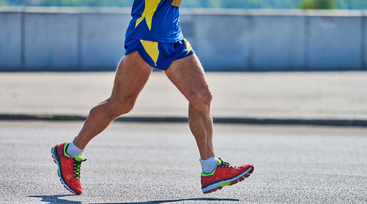 Läuferbeine in Bewegung mit bunten Laufschuhen, Jogging auf Asphalt