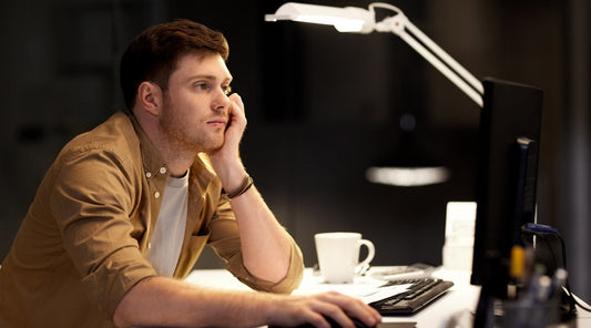 Mann starrt gelangweilt auf Bildschirm im Büro