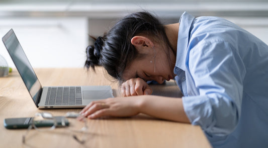 Erschöpfte Frau mit Burnout am Schreibtisch
