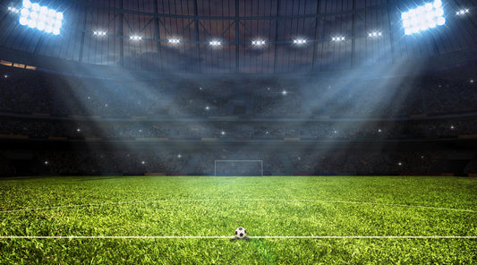 Fußballstadion bei Flutlicht mit Ball auf Rasen, Spielatmosphäre bei Nacht
