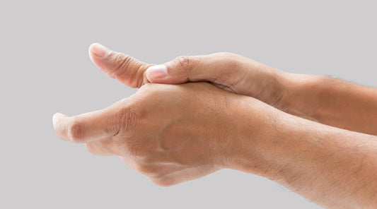 Mensch hält schmerzenden Daumen mit der anderen Hand fest