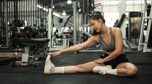 Frau macht Dehnübung im Fitnessstudio vor dem Workout