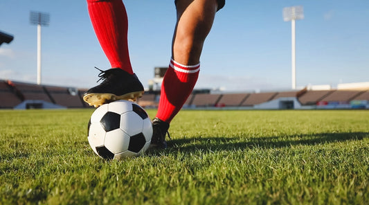 Fußballspieler stoppt Ball auf Rasen, Fokus auf Beine und Ballkontrolle