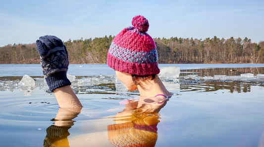 Frau beim Eisbaden mit Mütze und Handschuhen im Wintersee