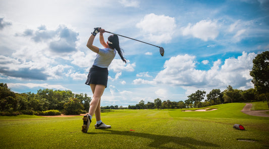 Golferin beim Abschlag auf grünem Golfplatz