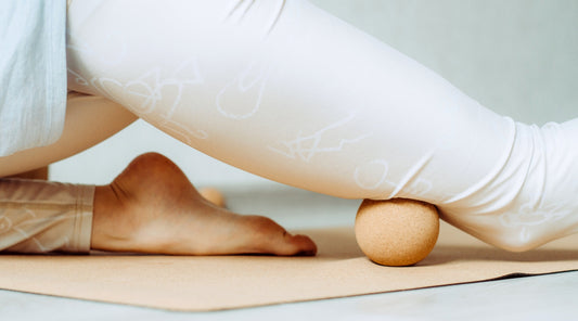 Nahaufnahme einer Faszienmassage mit Faszienball an der Wade auf einer Yogamatte