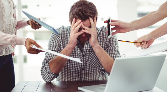 Gestresster Mann im Büro – zu viel Arbeit und Reizüberflutung als mögliche Ursache für Faszienverspannungen
