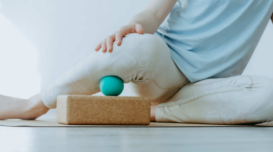 Faszientherapie mit Massageball unter dem Oberschenkel auf Korkblock zur Muskelentspannung