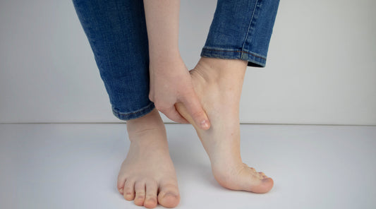 Frau hält sich schmerzenden Fuß wegen Fersenschmerzen