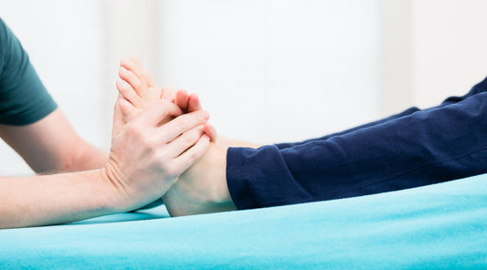 Physiotherapeut mobilisiert den Fuß eines Patienten – Therapie bei Fußschmerzen oder Bewegungseinschränkungen