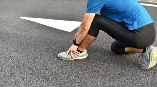 Jogger fasst sich an schmerzendes Sprunggelenk – Fußverletzung beim Sport oder Laufen