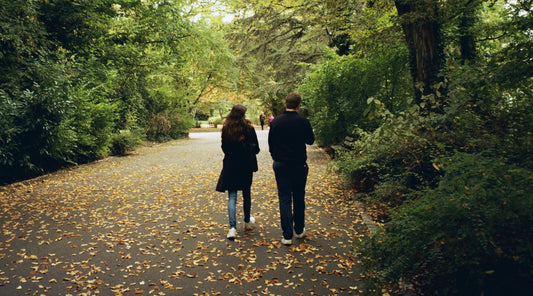 Paar spaziert durch einen grünen, herbstlichen Waldweg