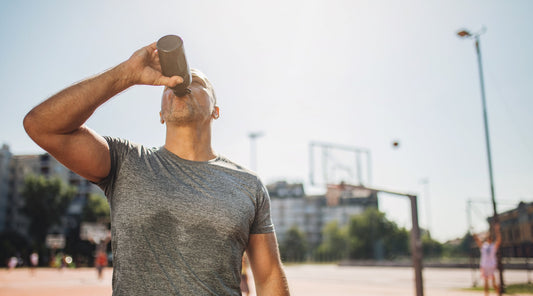 Sportlicher Mann trinkt Wasser nach dem Training auf dem Basketballplatz