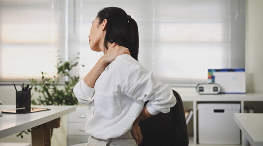 Frau mit Nackenschmerzen im Büro sitzt am Schreibtisch