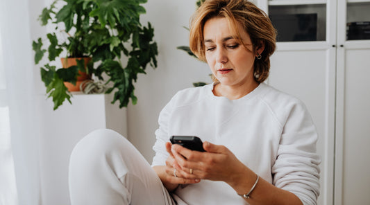 Frau mit Handynacken schaut konzentriert auf ihr Smartphone