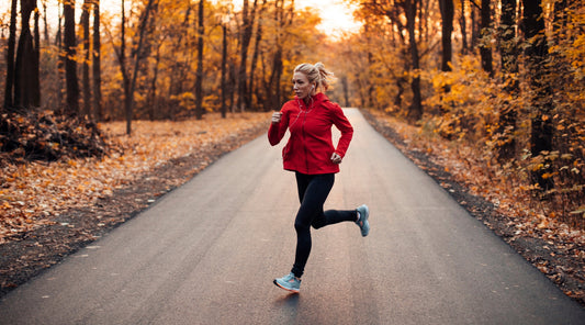 Frau am Joggen im Wald mit Herbstblättern