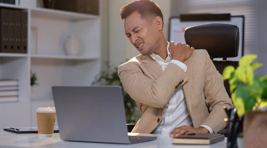 Geschäftsmann mit Schulterschmerzen am Schreibtisch