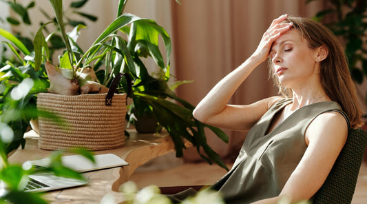 Frau mit stressbedingten Kopfschmerzen im Homeoffice“
