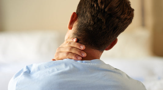 Mann greift sich an den Nacken wegen verspannungsbedingter Kopfschmerzen