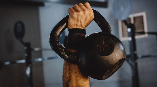 Kettlebell-Training im Fitnessstudio – starker Arm hält 24-kg-Kugel für funktionelles Krafttraining