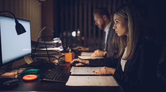 Frau und Mann arbeiten lange sitzend am Schreibtisch im Büro