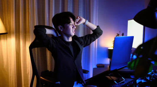 Müder Mann streckt sich nachts vor dem Computerbildschirm im Büro langes Sitzen