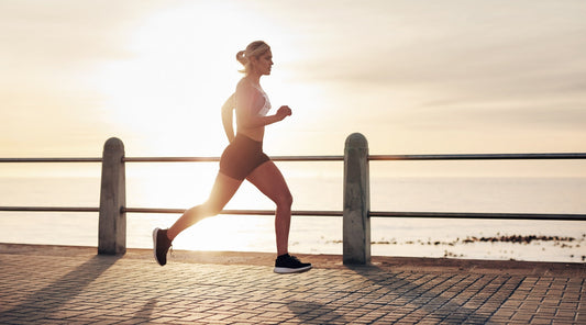 Frau beim Lauftraining am Meer bei Sonnenuntergang