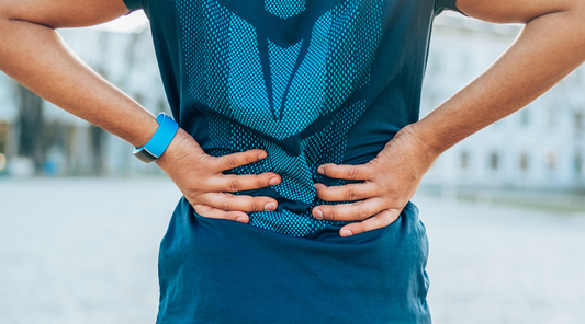 Mann mit Schmerzen im unteren Rücken nach dem Sport – Rückenschmerzen durch Überlastung oder Muskelverspannung