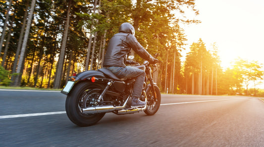 Motorradfahrer fährt auf Straße bei Sonnenuntergang
