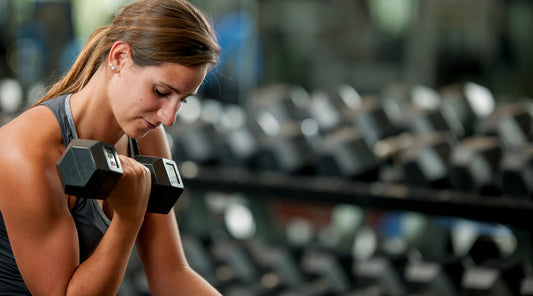Frau trainiert mit Kurzhantel im Fitnessstudio Krafttraining