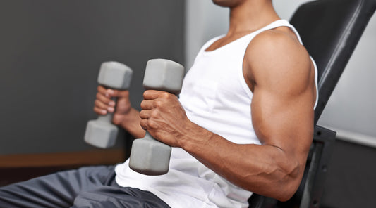 Mann trainiert mit Kurzhanteln im Fitnessstudio
