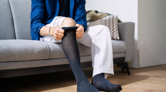 Mann zieht Kompressionsstrümpfe gegen Ödeme an