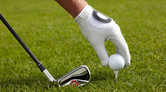 Hand setzt Golfball auf Tee mit Schläger