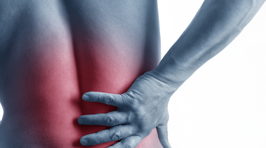 Person hält schmerzenden unteren Rücken, rote Markierung hebt Schmerzbereich hervor.