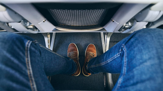 Beine eines Passagiers mit wenig Beinfreiheit im Flugzeug – Risiko für schwere Beine auf Reisen