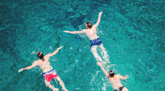 Drei Personen schwimmen im türkisblauen Meer