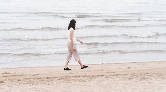 Frau spaziert entspannt am Strand entlang