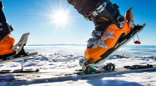 Orangene Skischuhe werden in Skibindung eingerastet