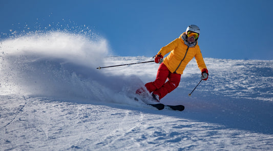 Skifahrer in gelber Jacke fährt durch Pulverschnee