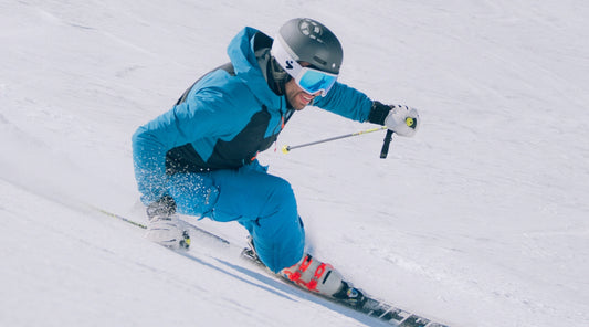 Snowboarder in blauem Anzug fährt im Schnee mit Hand am Boden