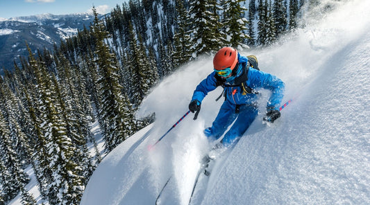 Skifahrer fährt im Tiefschnee bergab in den Alpen.
