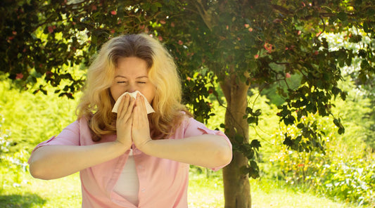 Frau niest wegen Pollenallergie im Garten