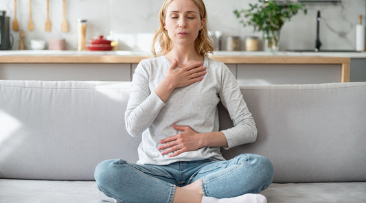 Frau macht Atemübung gegen Stress im Wohnzimmer